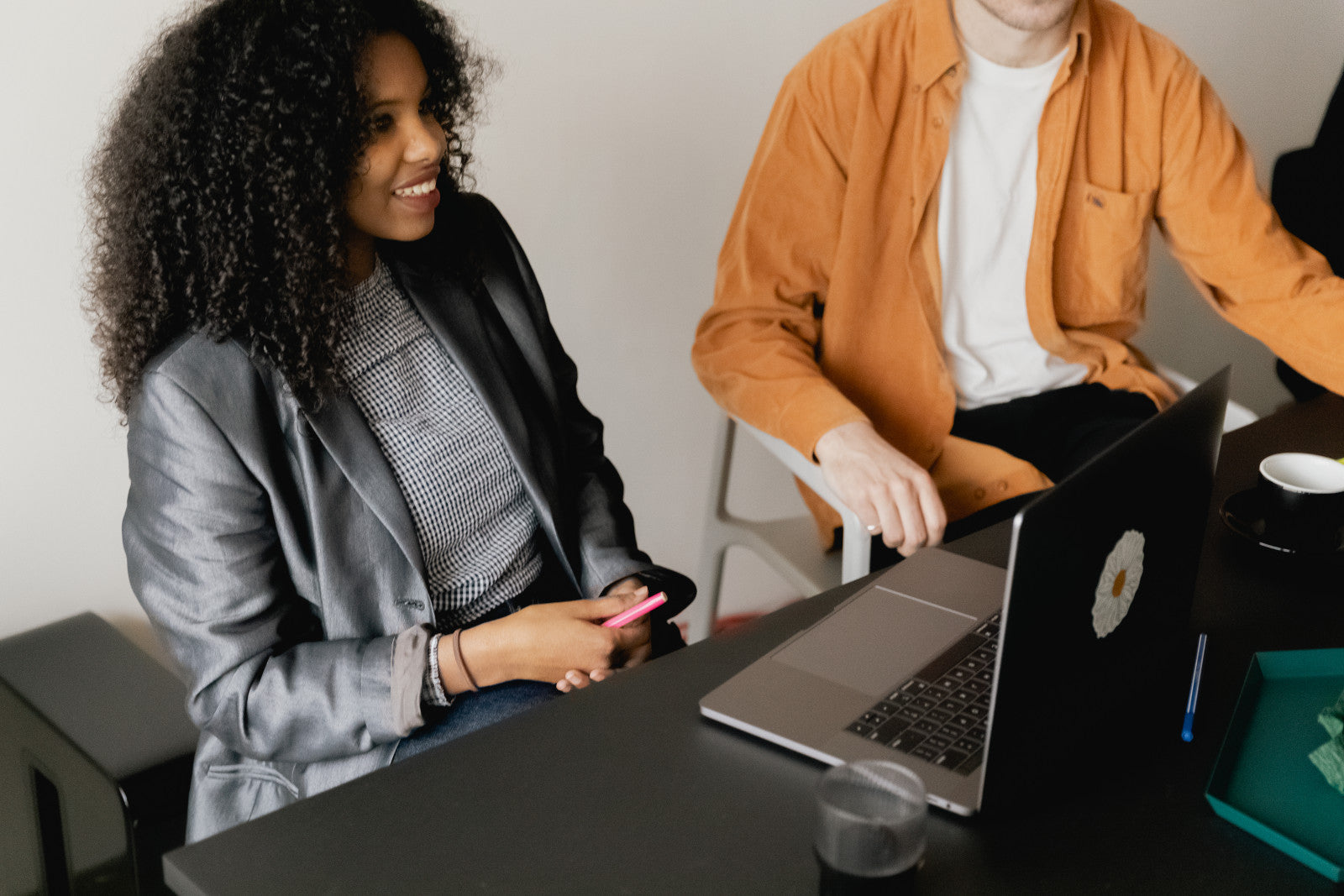 Woman at desk with laptop, smiling.
